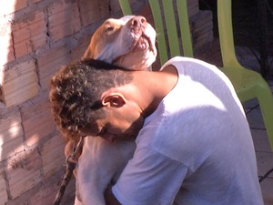 Pai da criança morta, abraçado ao cão da família (Foto: Reprodução/TV Tapajós)